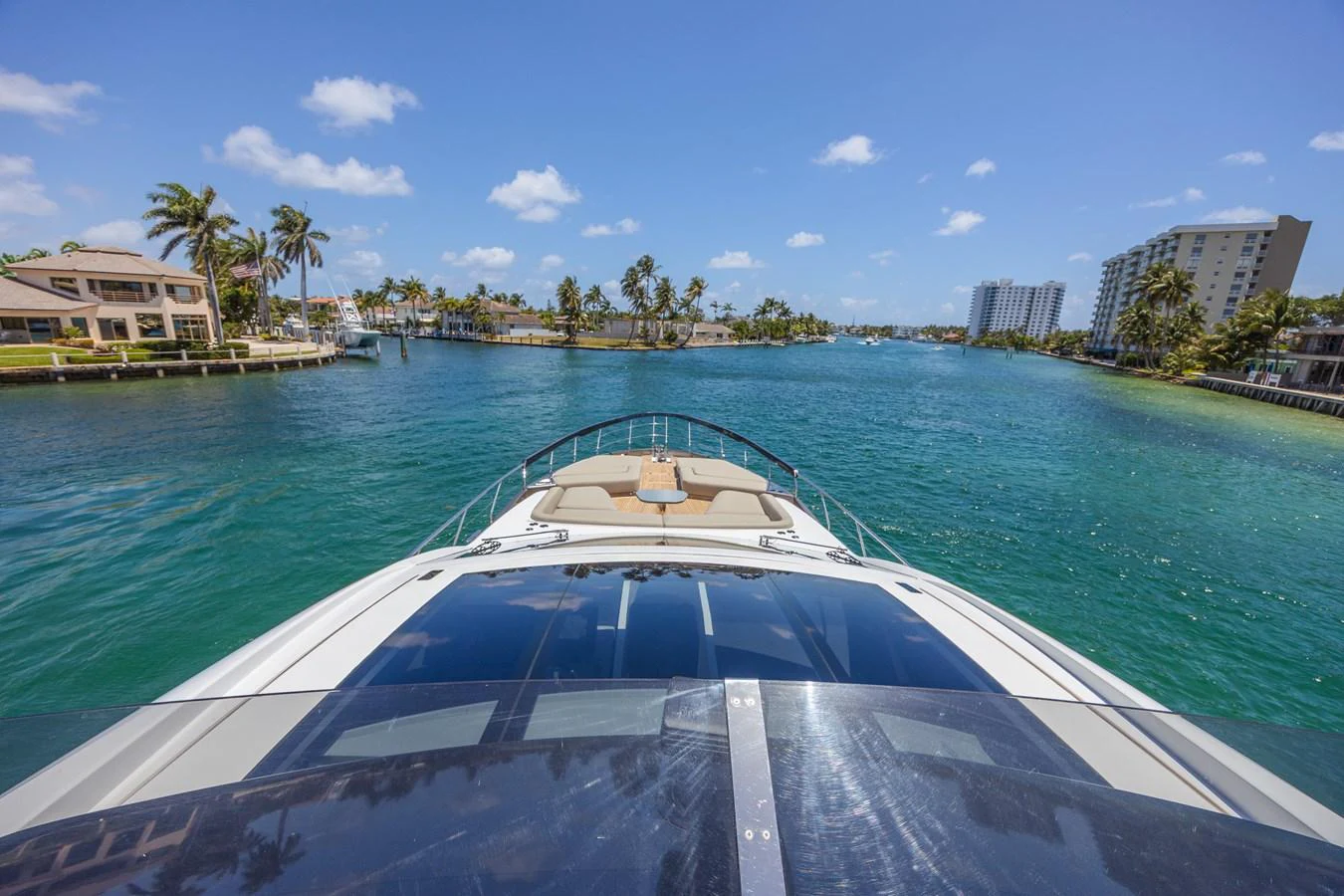 The yacht cruises through a serene waterway with clear blue skies and lush surroundings. aboard NO TIME TO DIE Yacht for Sale
