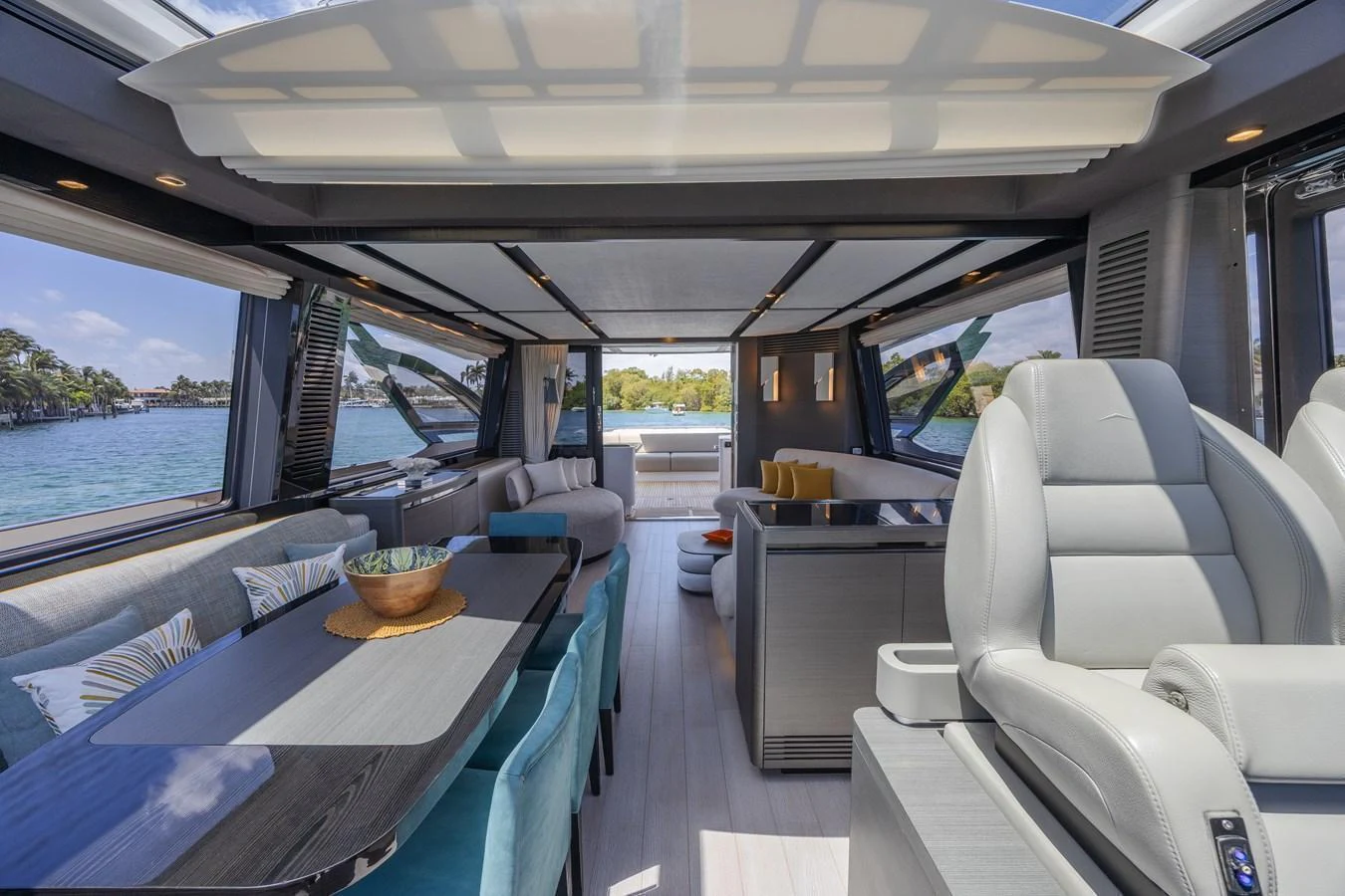 The yacht's salon features luxurious seating, a dining area, and expansive windows offering stunning views. aboard NO TIME TO DIE Yacht for Sale