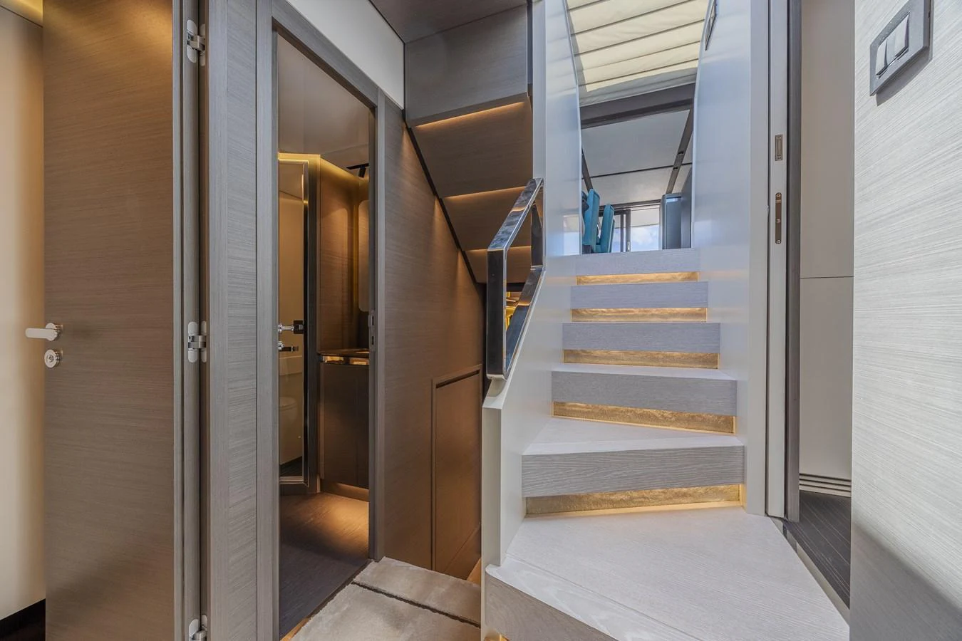 The image showcases a modern yacht interior with a sleek staircase leading to an upper level. aboard NO TIME TO DIE Yacht for Sale