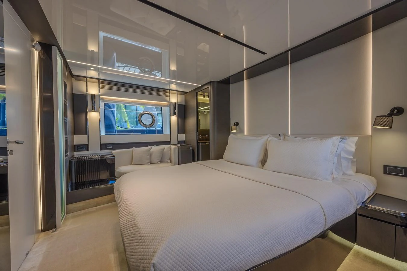 The stateroom features a luxurious bed with modern lighting and a large window providing natural light. aboard NO TIME TO DIE Yacht for Sale