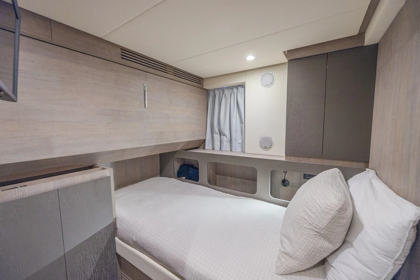 A cozy stateroom featuring a single bed with modern wood finishes and soft lighting. aboard NO TIME TO DIE Yacht for Sale