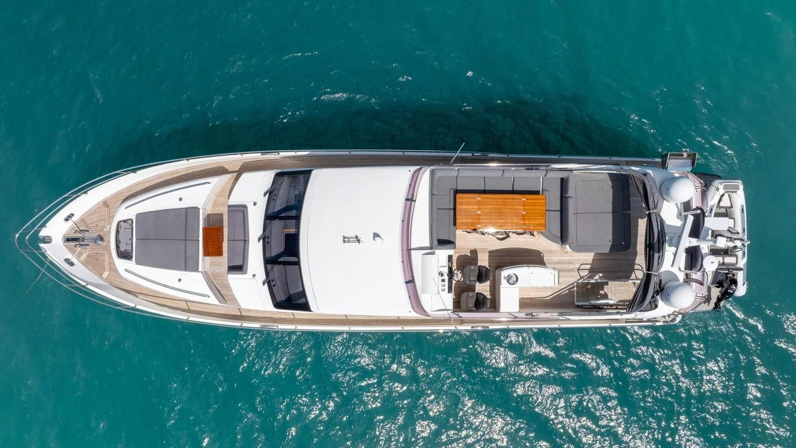 A sleek and modern yacht is captured from above, showcasing its spacious deck and luxurious amenities. aboard ABOUT TIME Yacht for Sale
