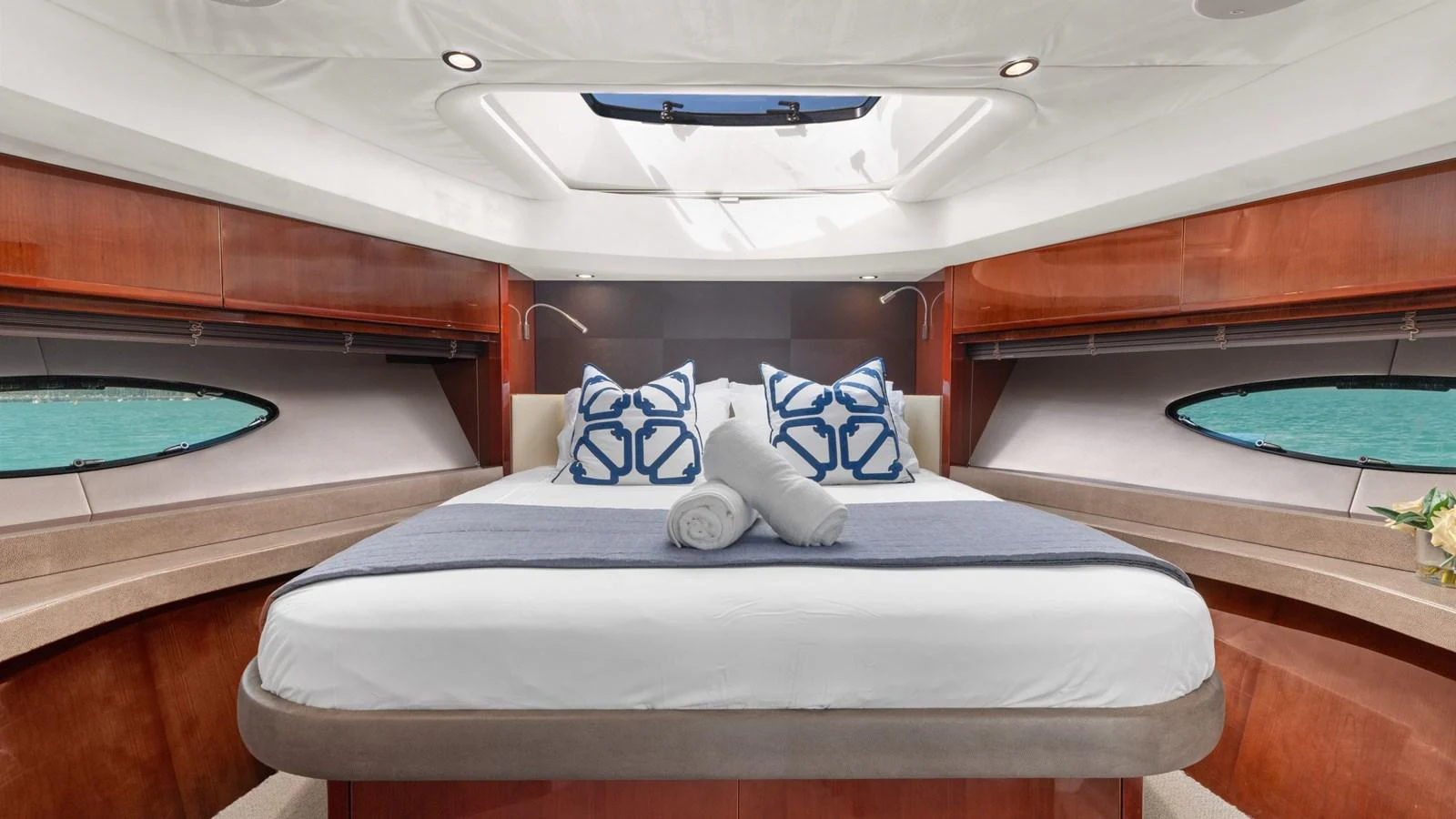 The stateroom features a luxurious bed with elegant bedding and ample natural light from the surrounding windows. aboard ABOUT TIME Yacht for Sale