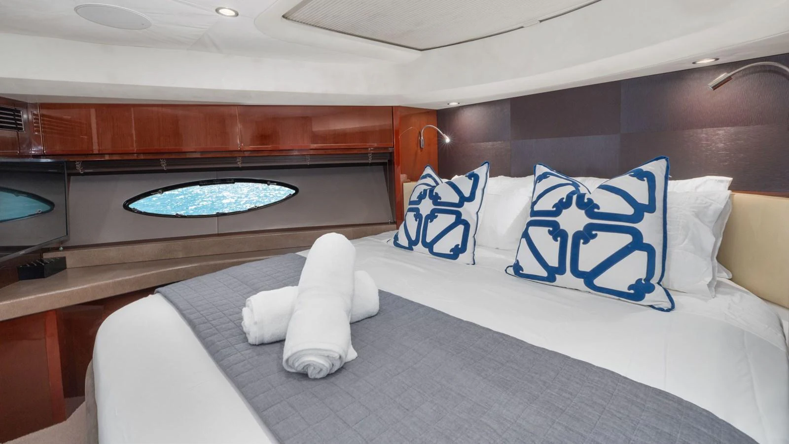 The stateroom features a luxurious bed with elegant linens and a view of the sea through the window. aboard ABOUT TIME Yacht for Sale