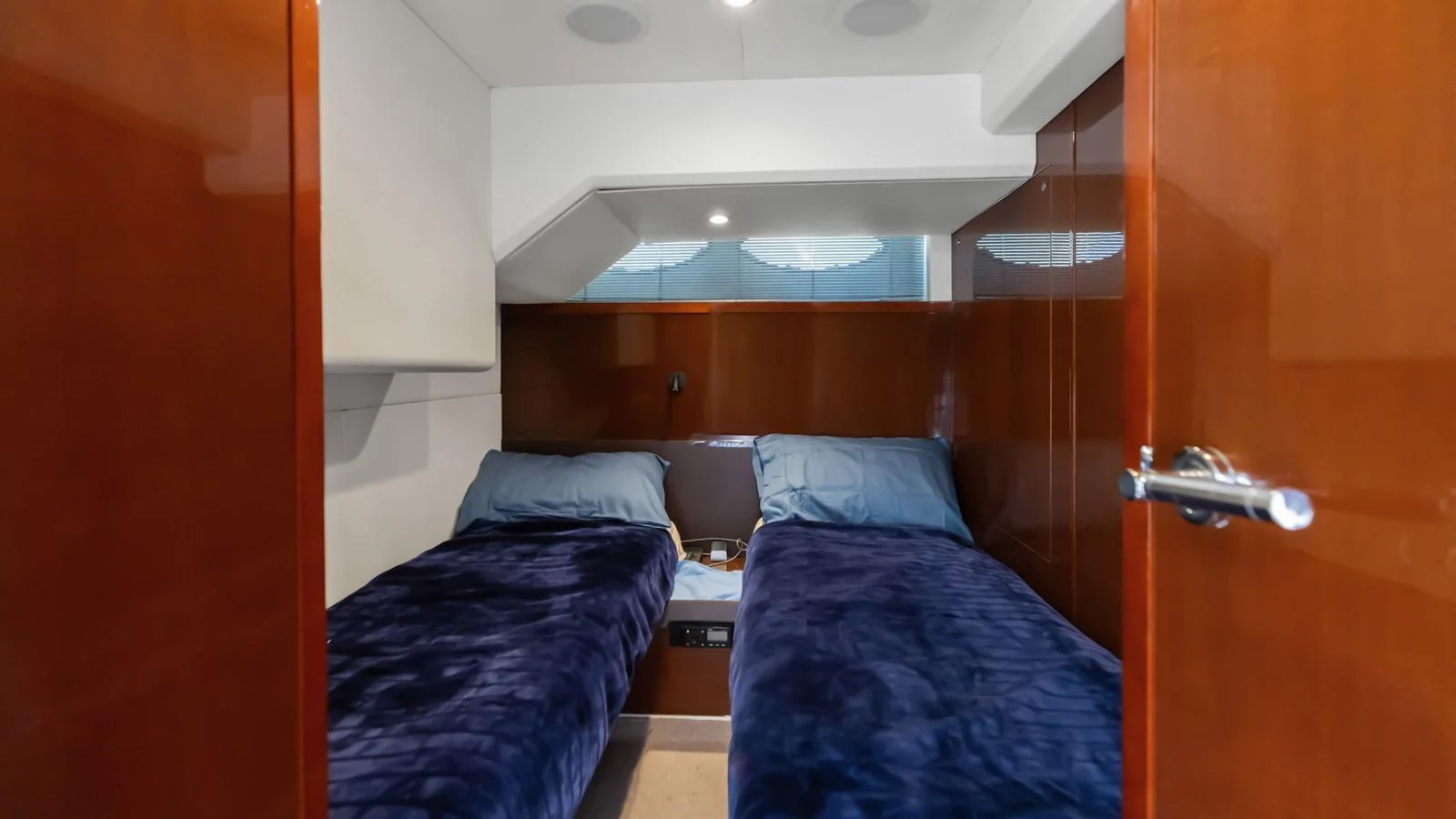 The twin stateroom features two comfortable beds with plush blue bedding and warm wood paneling. aboard ABOUT TIME Yacht for Sale