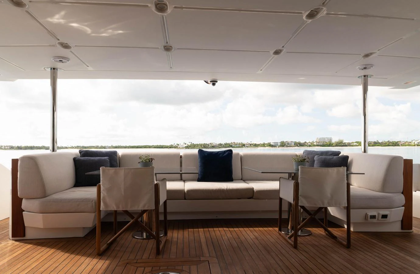 a white couch and chairs in a room with a wood floor and a large body of water in aboard CARPE DIEM Yacht for Sale