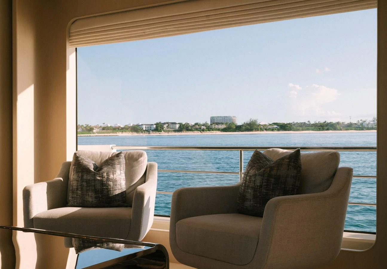 a couple of couches facing a large window with a body of water in the background aboard CARPE DIEM Yacht for Sale