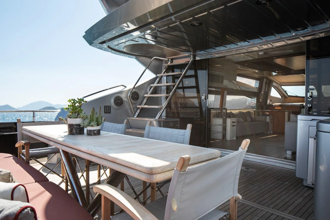 The aft deck features a stylish outdoor dining area with a view into the luxurious interior. aboard AMARA Yacht for Sale