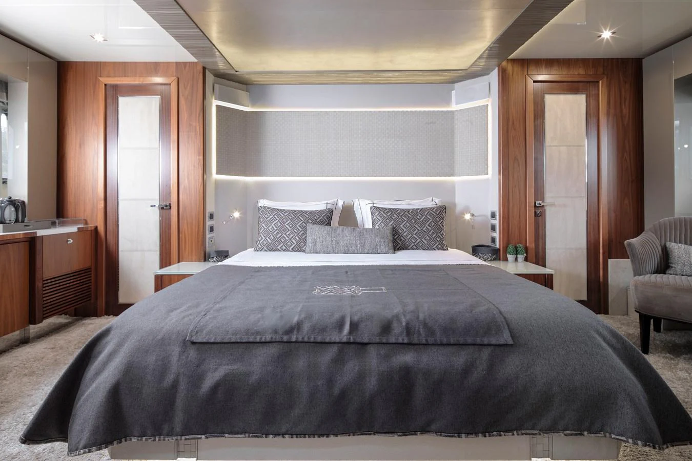The master stateroom features a luxurious bed with elegant wood finishes and modern lighting. aboard AMARA Yacht for Sale