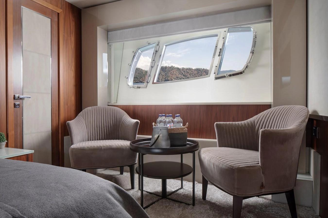 A cozy stateroom with two armchairs and a round table, featuring a scenic view through the window. aboard AMARA Yacht for Sale