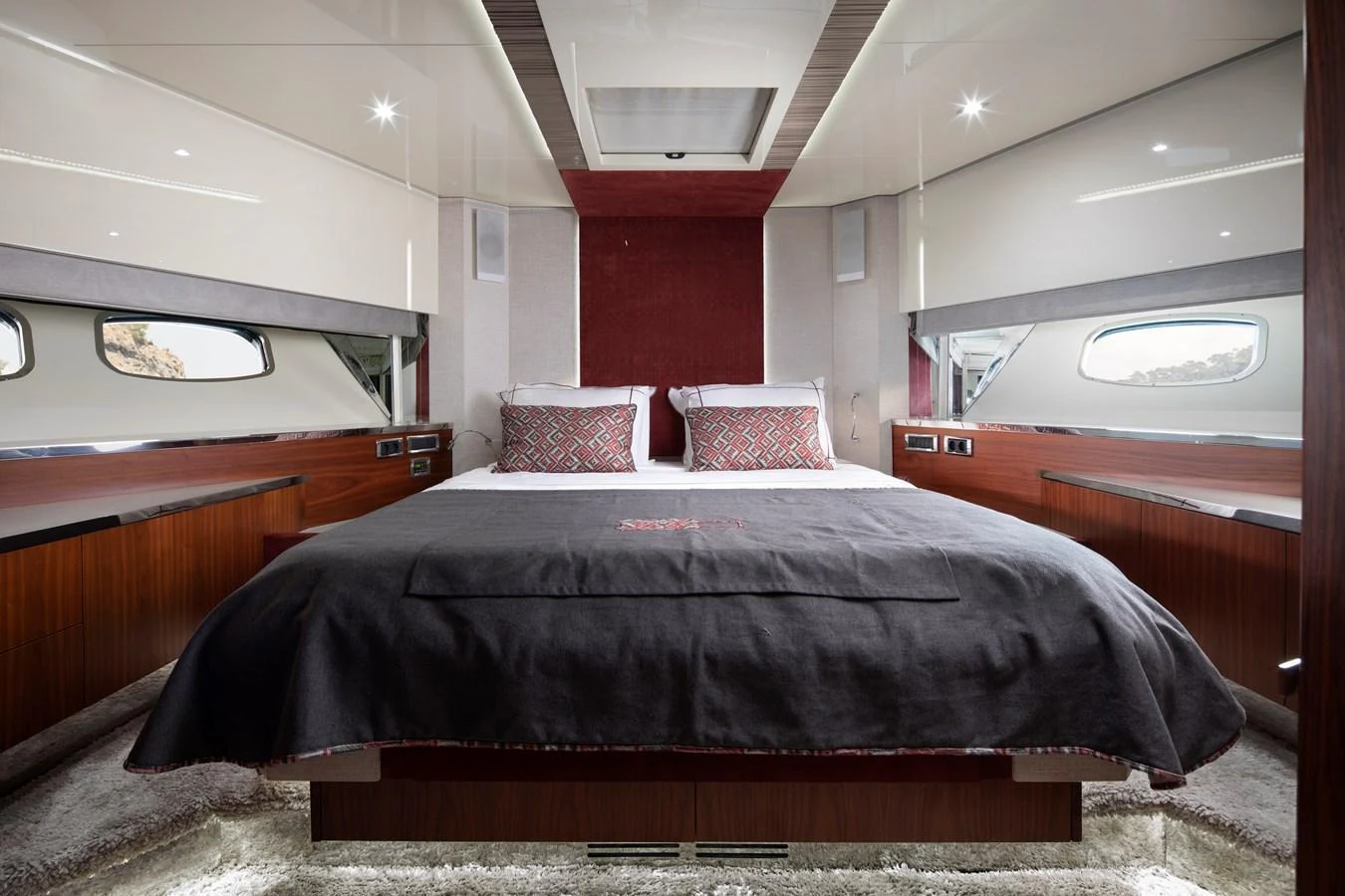 The stateroom features a plush bed with elegant bedding, surrounded by sleek wood paneling and large windows for natural light. aboard AMARA Yacht for Sale
