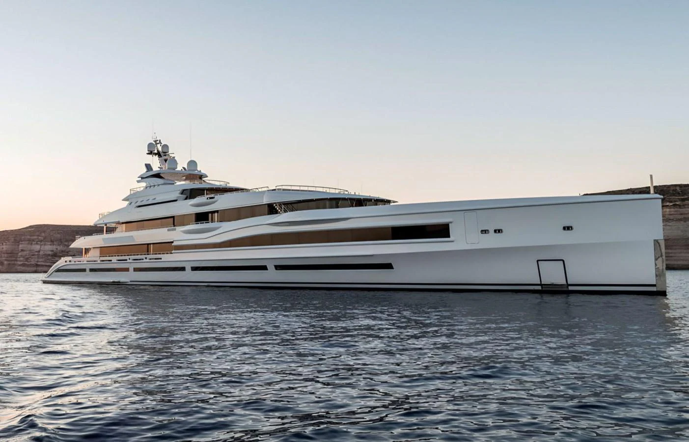 A sleek and modern yacht glides gracefully on calm waters at sunset. aboard LANA Yacht for Sale