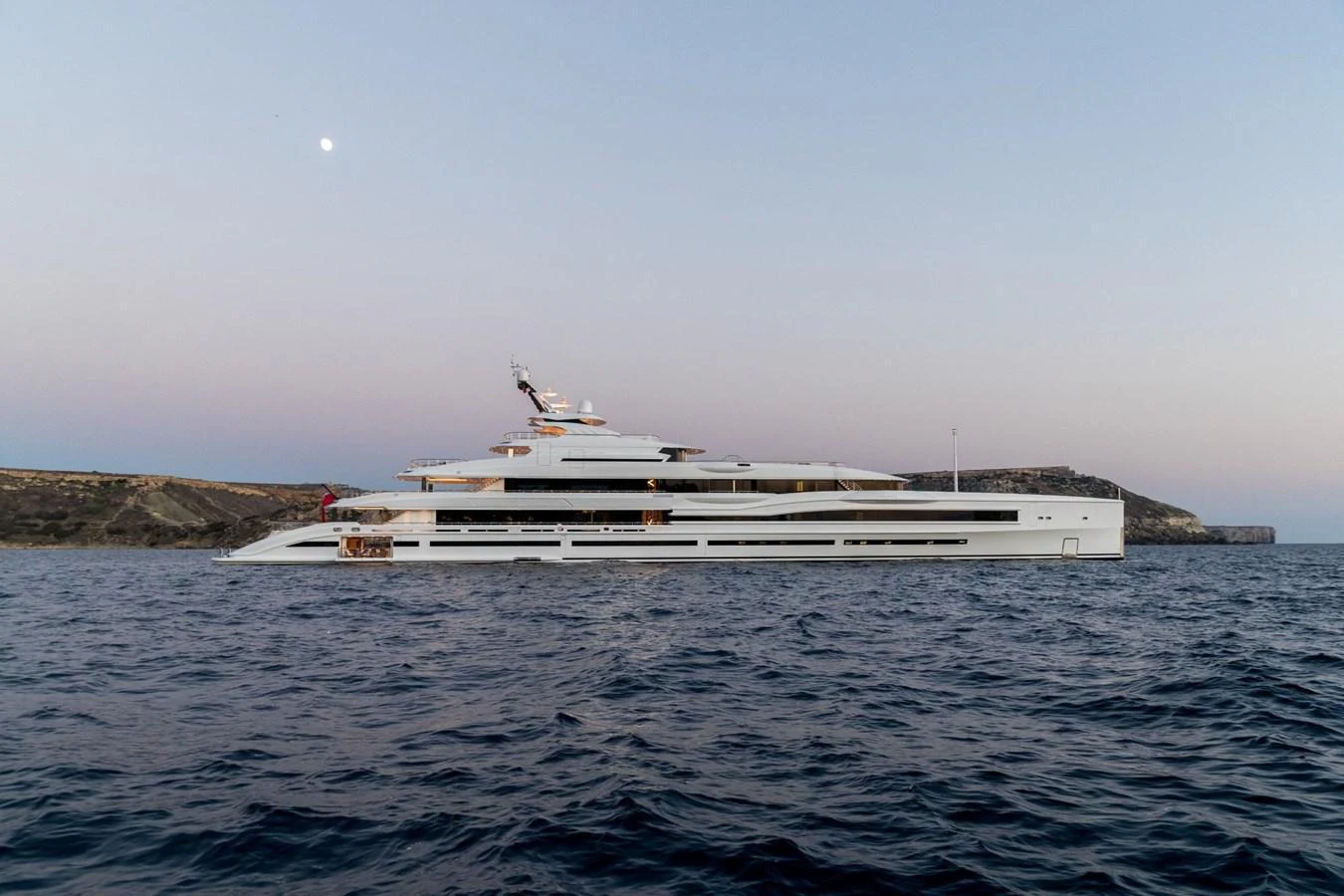A sleek and modern yacht cruises gracefully on the open water at dusk. aboard LANA Yacht for Sale