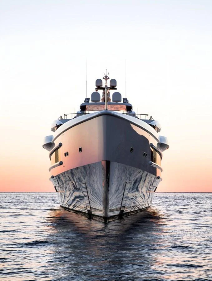 A stunning yacht is captured head-on, reflecting the serene waters at sunset. aboard LANA Yacht for Sale