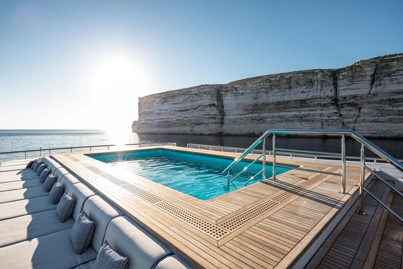 The yacht features a stunning pool deck with a spacious swimming pool and luxurious sun loungers, set against a breathtaking coastal backdrop. aboard LANA Yacht for Sale