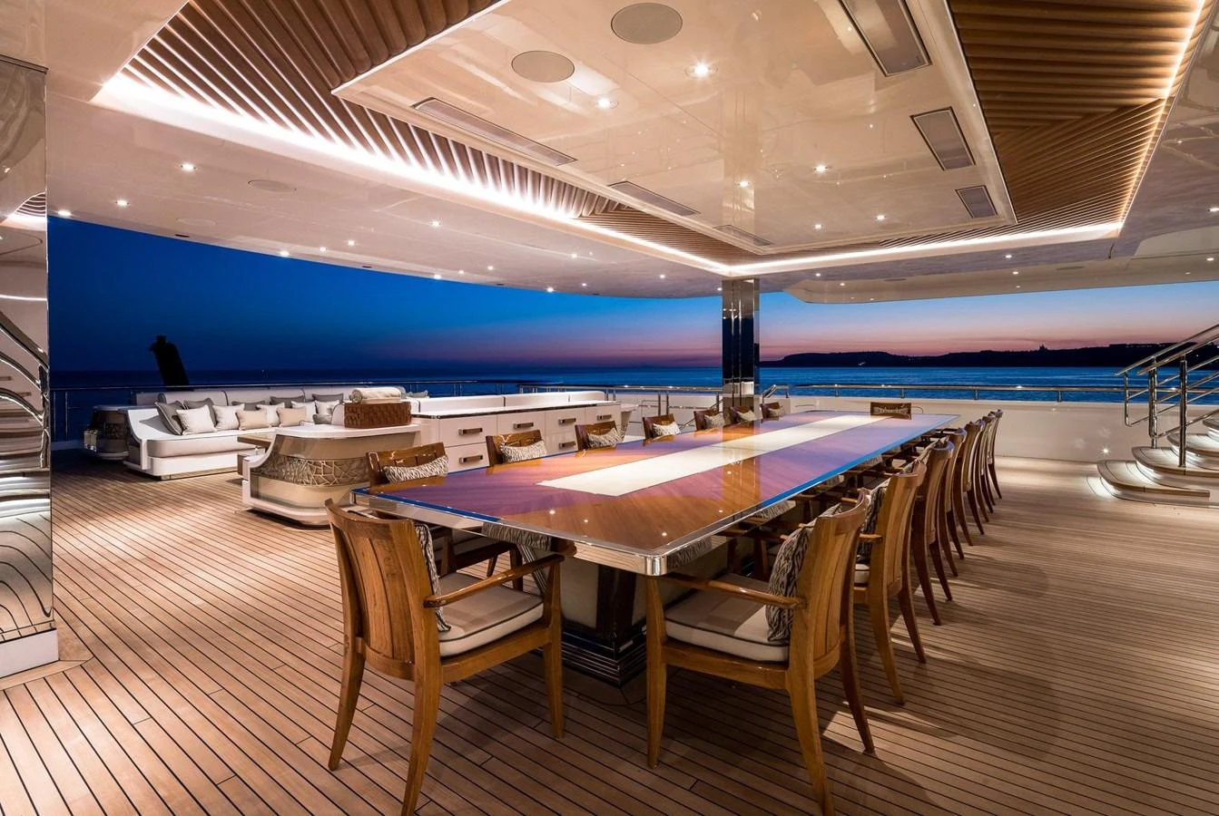 The aft deck features an elegant dining area with a stunning view of the sunset over the water. aboard LANA Yacht for Sale