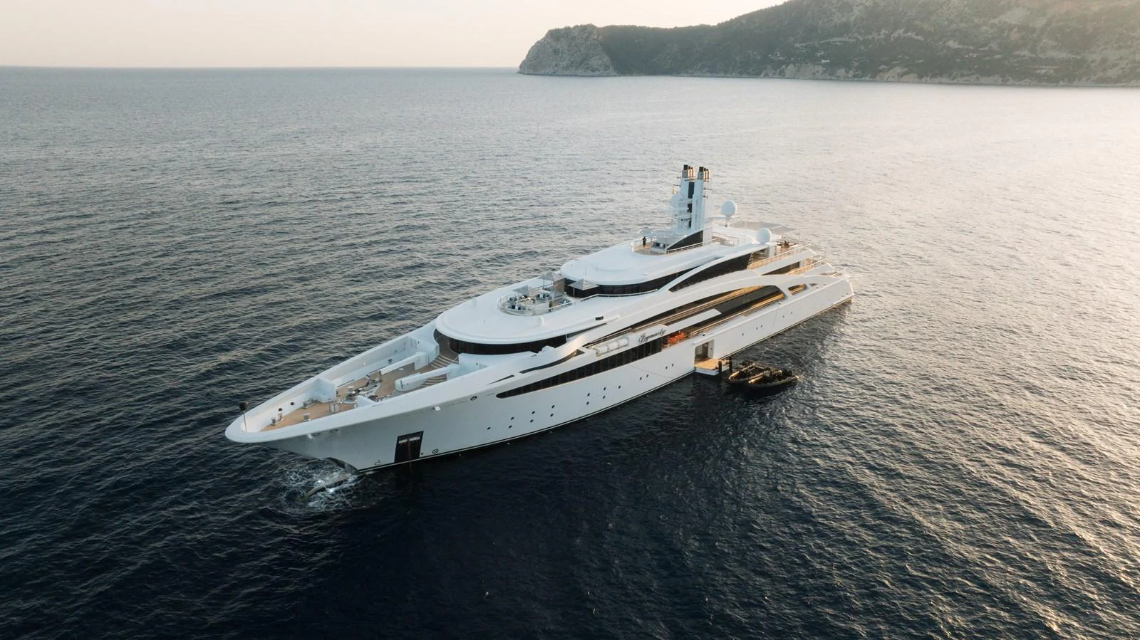 A stunning yacht glides through serene waters with a picturesque coastline in the background. aboard I DYNASTY Yacht for Sale