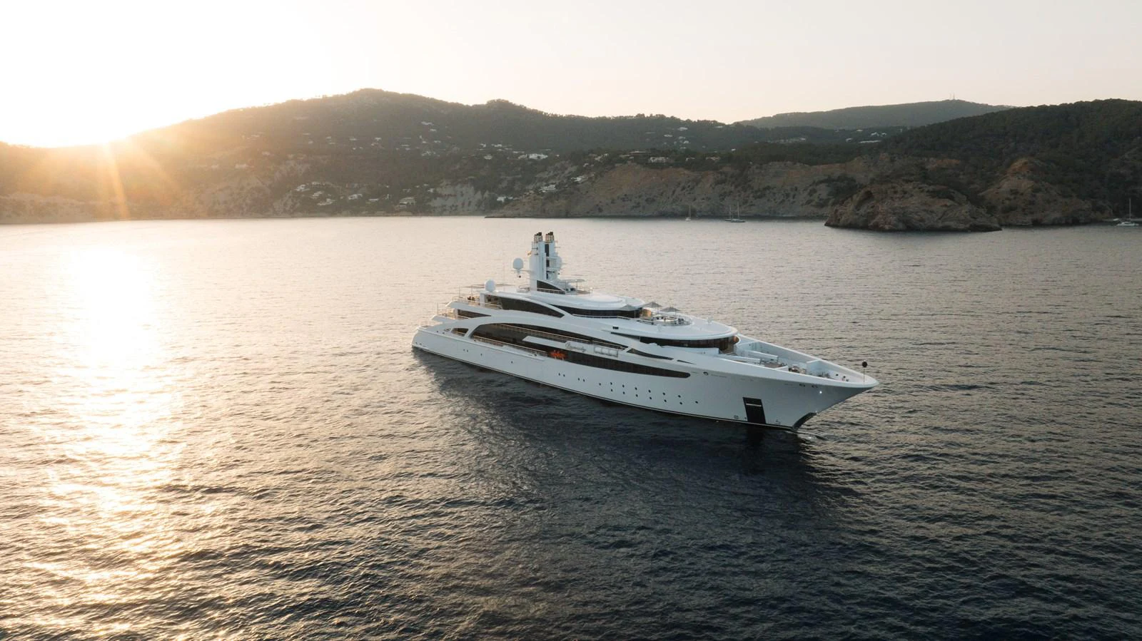 A sleek and luxurious yacht glides gracefully on calm waters with a scenic coastal backdrop. aboard I DYNASTY Yacht for Sale