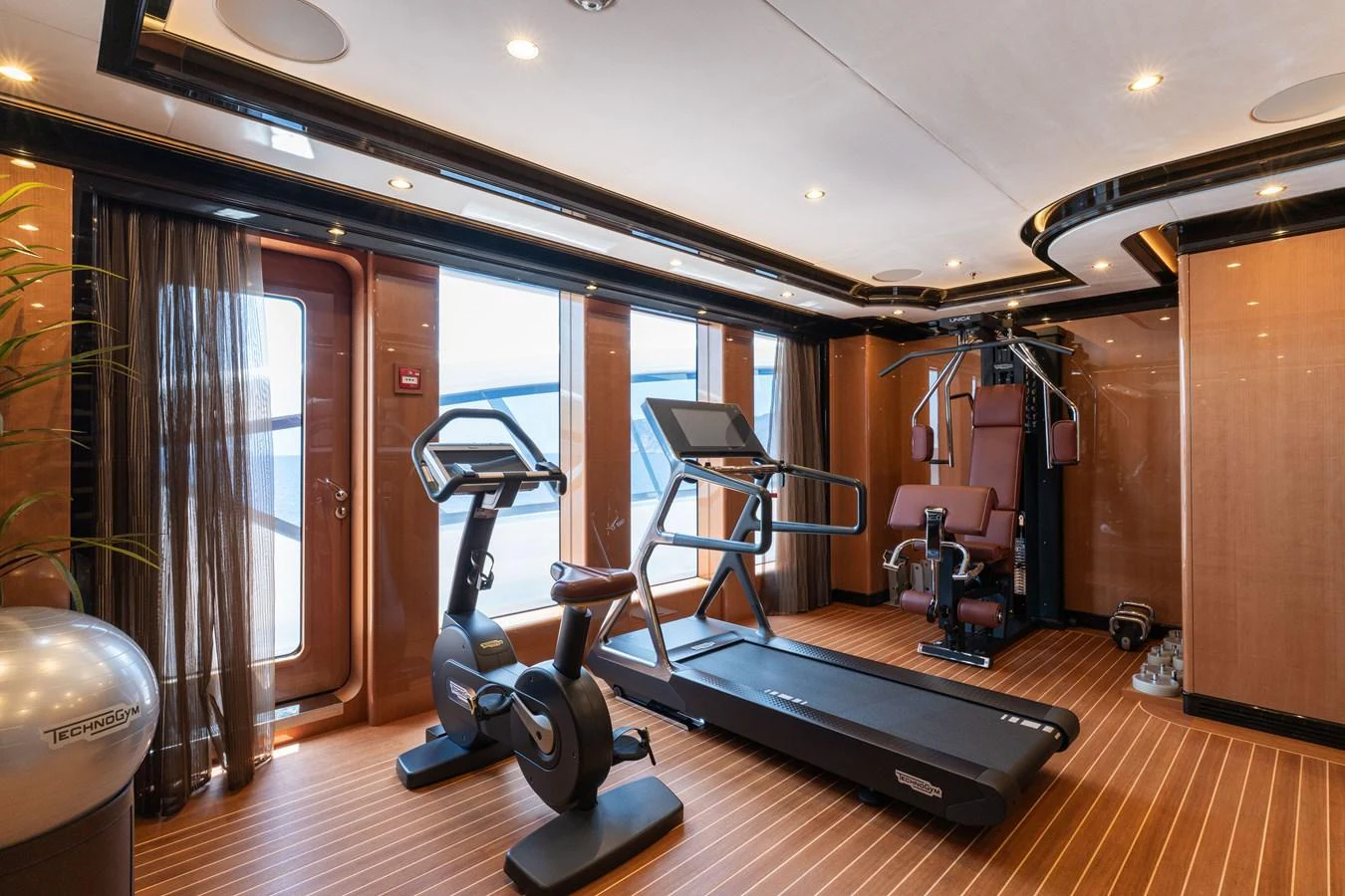 The yacht's gym is equipped with modern fitness machines and offers a bright, inviting space for workouts. aboard I DYNASTY Yacht for Sale