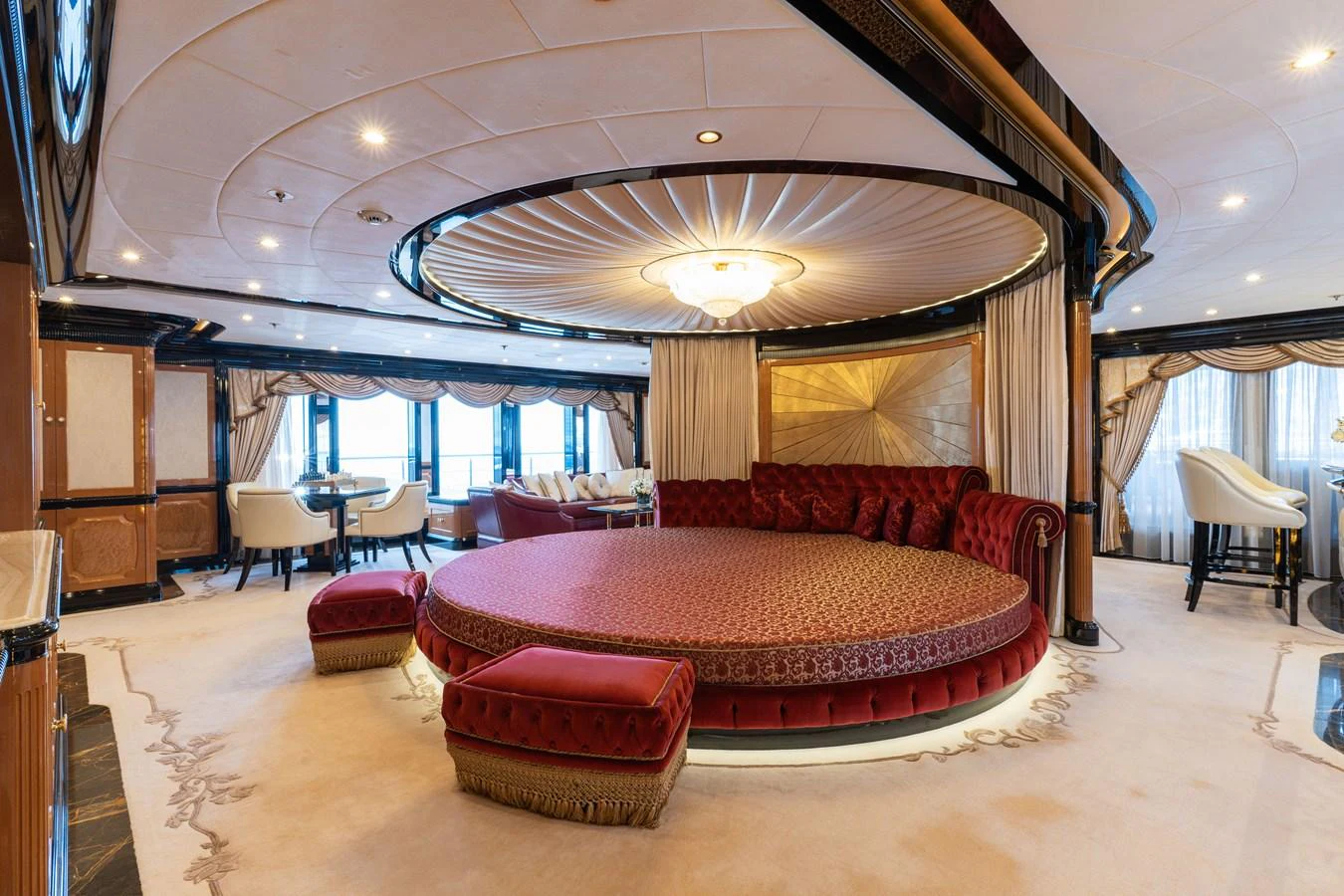 The luxurious salon features an opulent circular seating area with plush red upholstery and elegant decor. aboard I DYNASTY Yacht for Sale