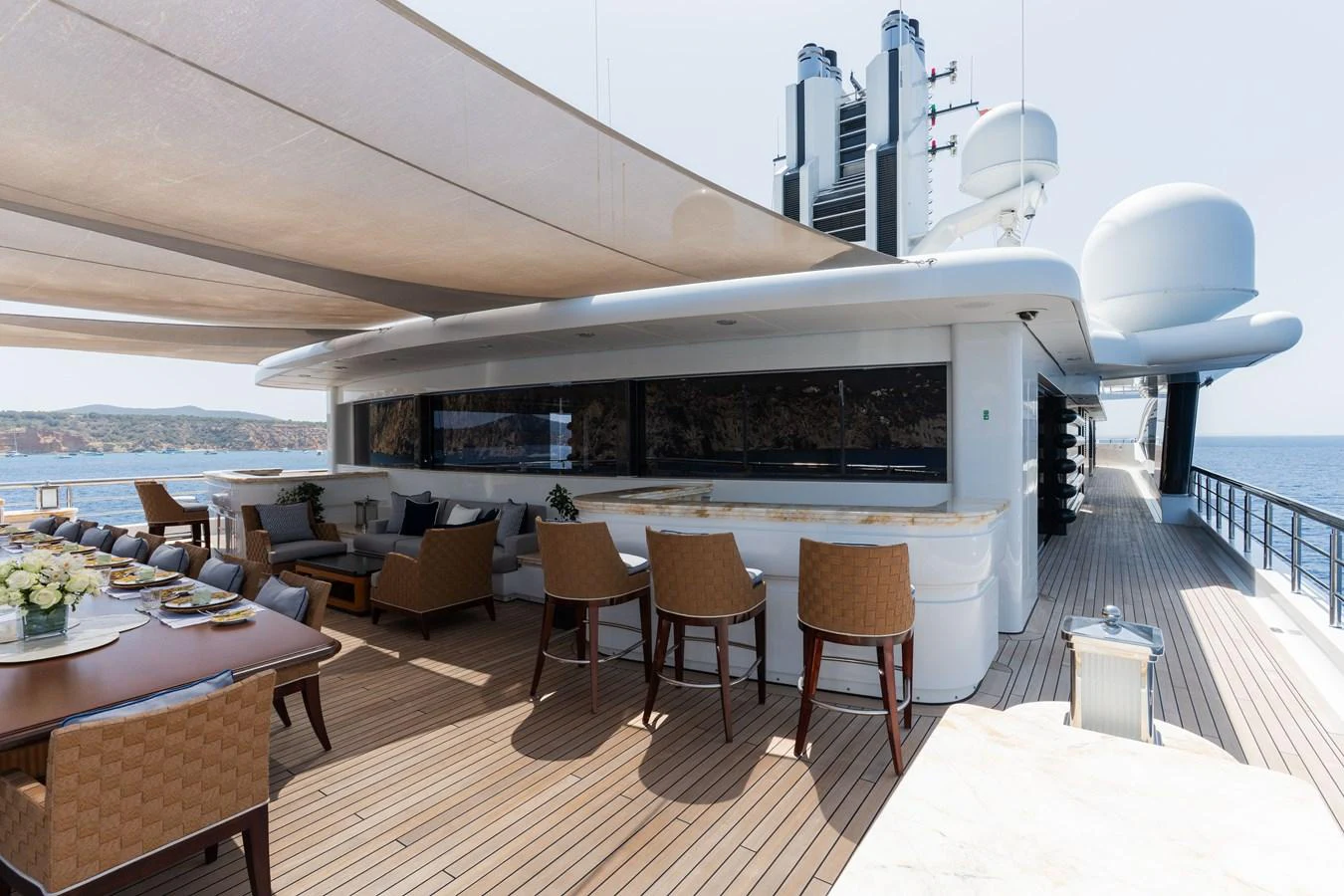 The aft deck features a spacious seating area with a bar and dining table, perfect for outdoor entertaining. aboard I DYNASTY Yacht for Sale