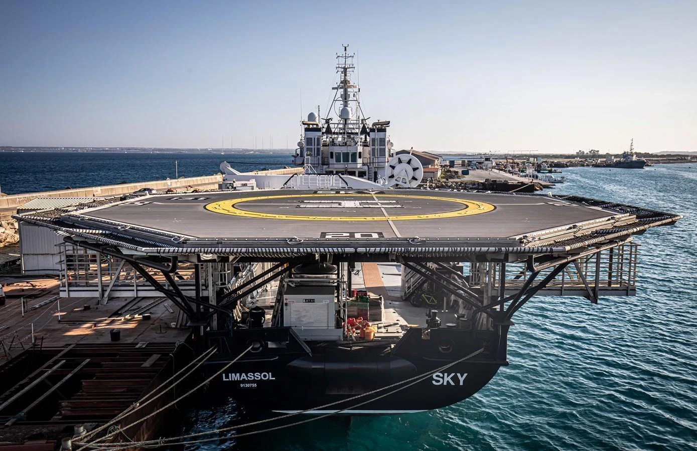 A large yacht with a prominent helipad docked at a marina. aboard SKY Yacht for Sale