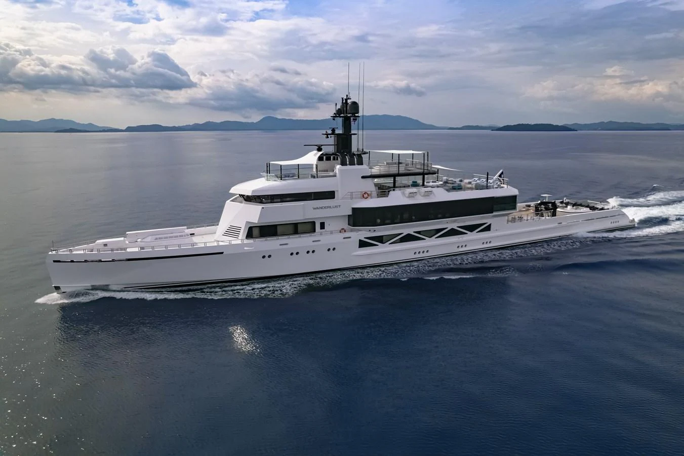 A sleek and modern yacht cruises smoothly on calm waters under a partly cloudy sky. aboard WANDERLUST Yacht for Sale
