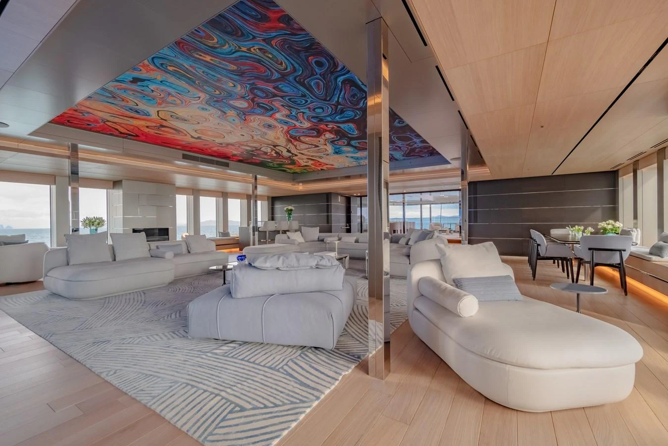 The spacious salon features modern furnishings and a striking ceiling mural, offering a luxurious and artistic ambiance. aboard WANDERLUST Yacht for Sale