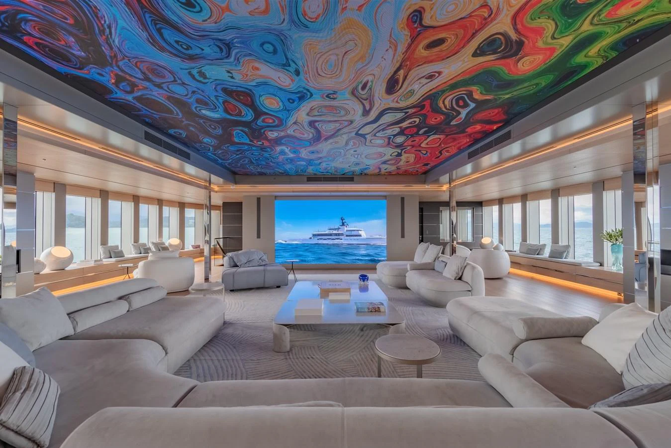 The spacious salon features luxurious seating and a vibrant, artistic ceiling design. aboard WANDERLUST Yacht for Sale