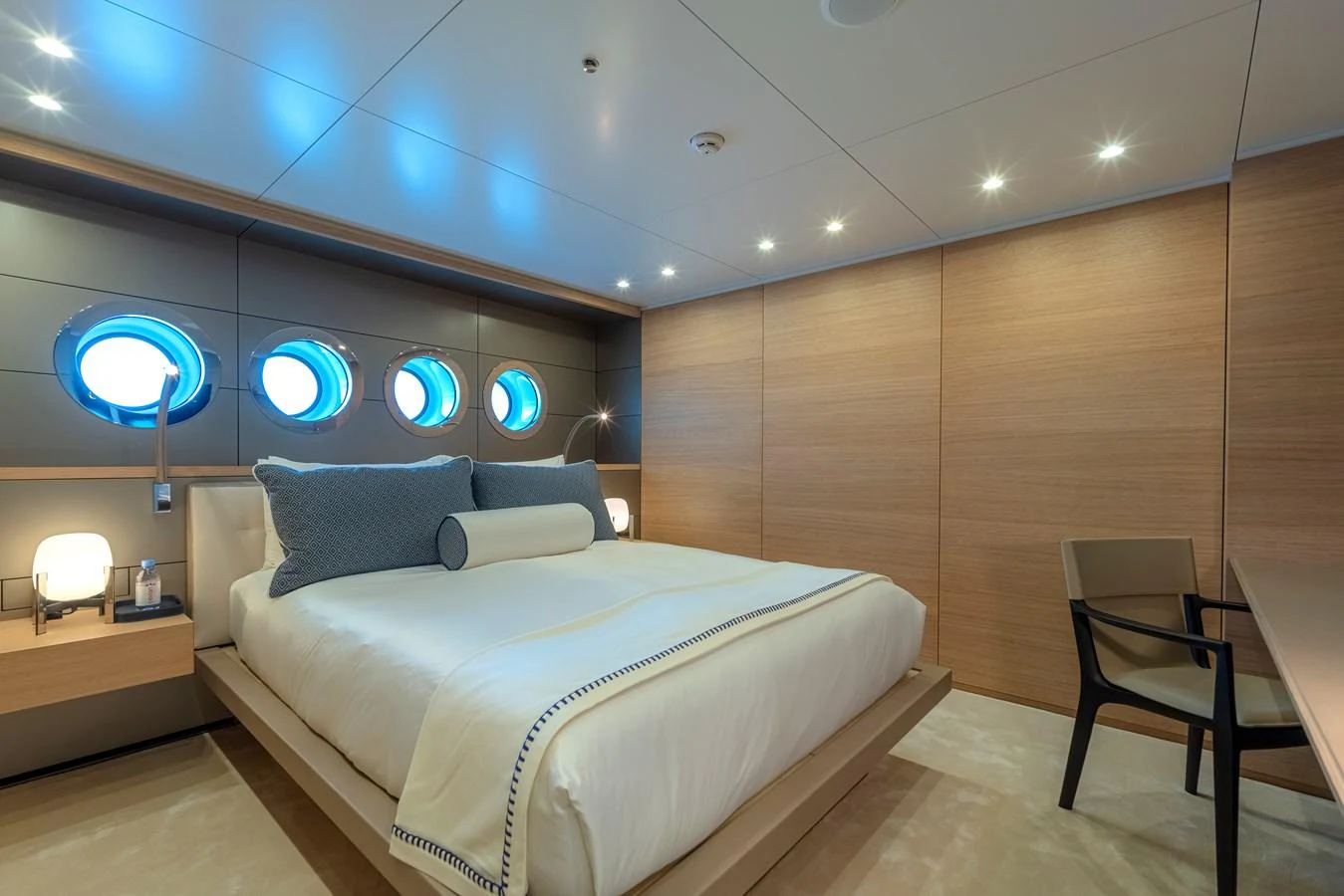 The stateroom features a luxurious bed with modern furnishings and ambient lighting. aboard WANDERLUST Yacht for Sale