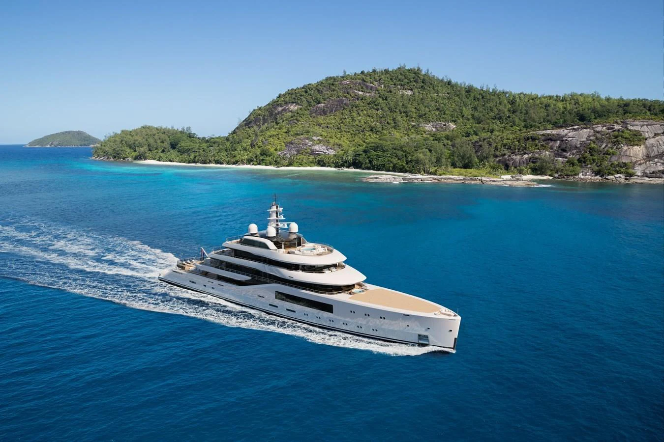 A luxurious yacht cruising through pristine blue waters with a scenic island backdrop. aboard AMELS 80 Yacht for Sale
