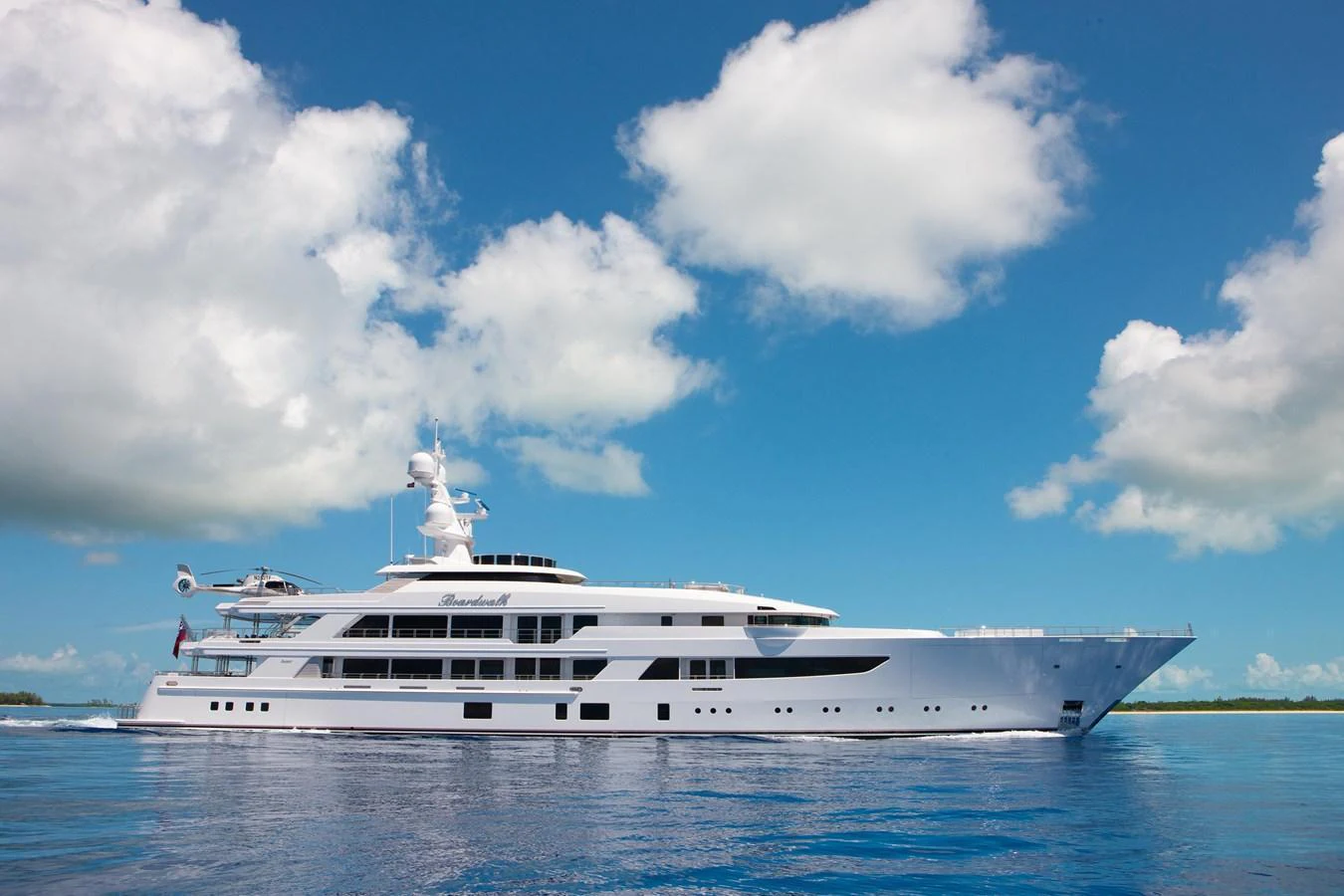 A stunning yacht glides gracefully on calm waters under a bright blue sky with scattered clouds. aboard BOARDWALK V Yacht for Sale
