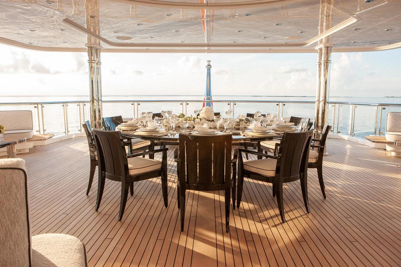 The aft deck features an elegant dining area with a large table and comfortable chairs, perfect for alfresco meals with a stunning sea view. aboard BOARDWALK V Yacht for Sale