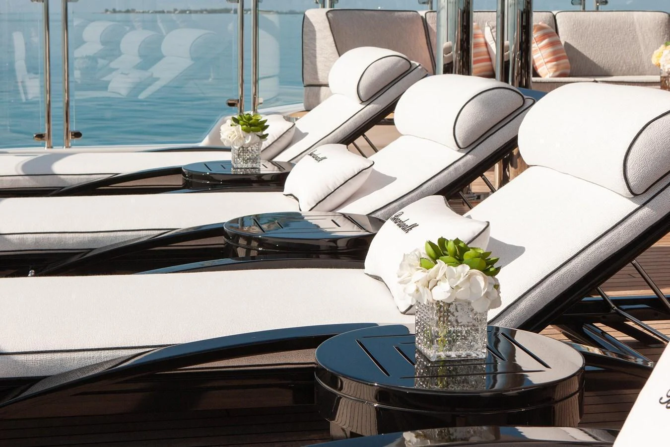 The sundeck features luxurious loungers with plush cushions and elegant floral arrangements, perfect for relaxation. aboard BOARDWALK V Yacht for Sale