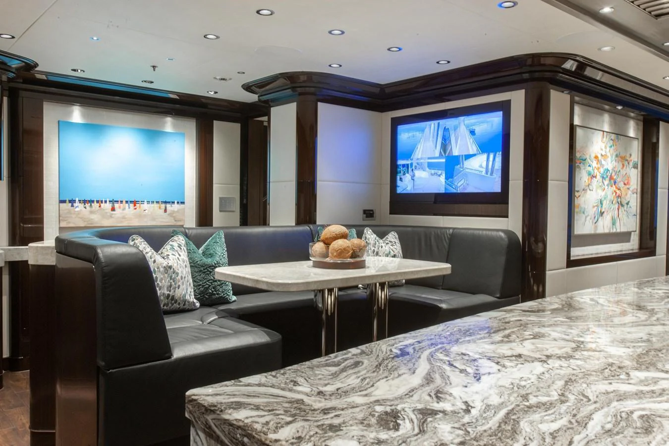 The yacht's salon features a luxurious seating area with a marble table and modern artwork. aboard BOARDWALK V Yacht for Sale