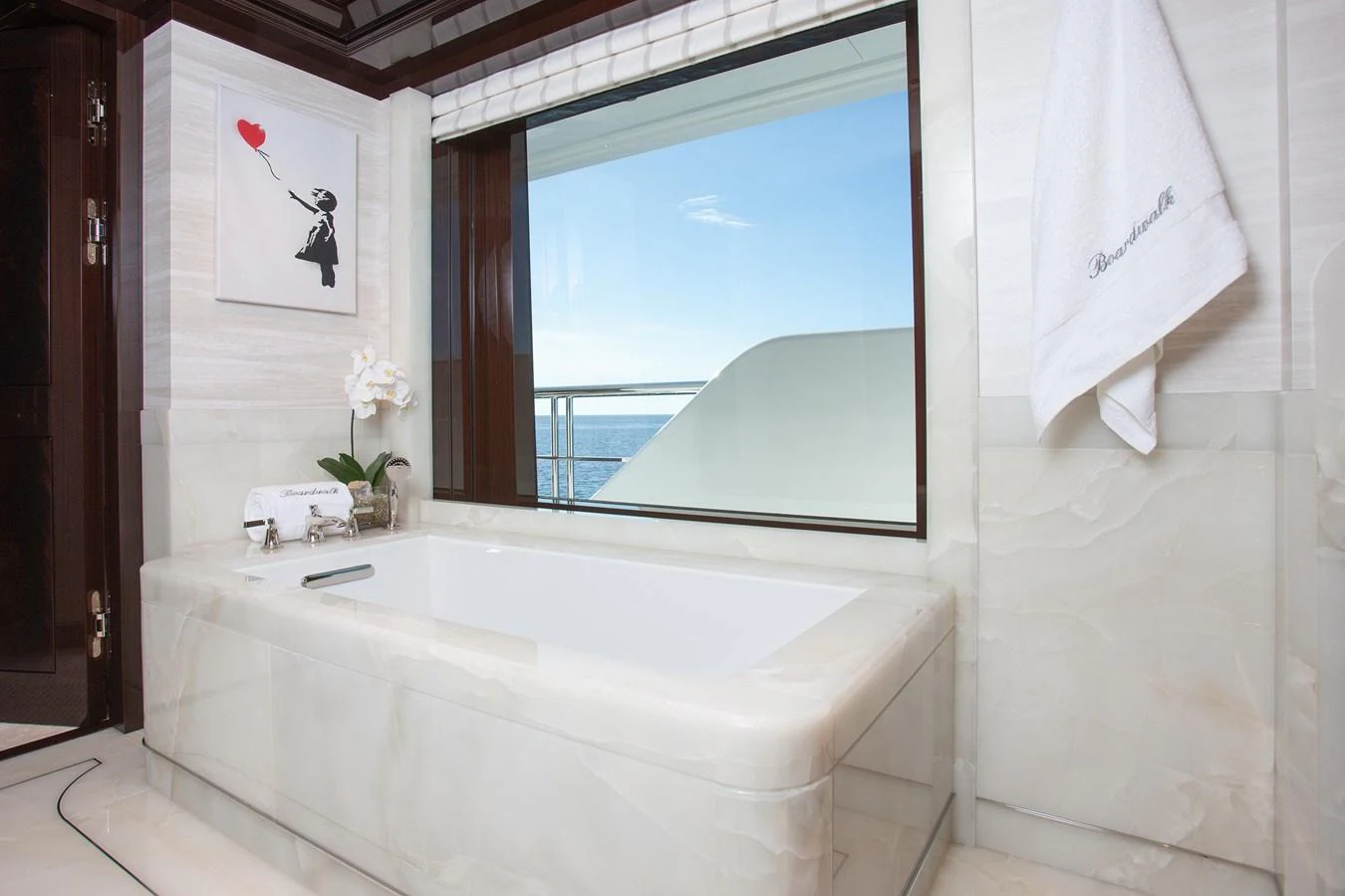 This luxurious yacht bathroom features a large bathtub with a view of the ocean. aboard BOARDWALK V Yacht for Sale
