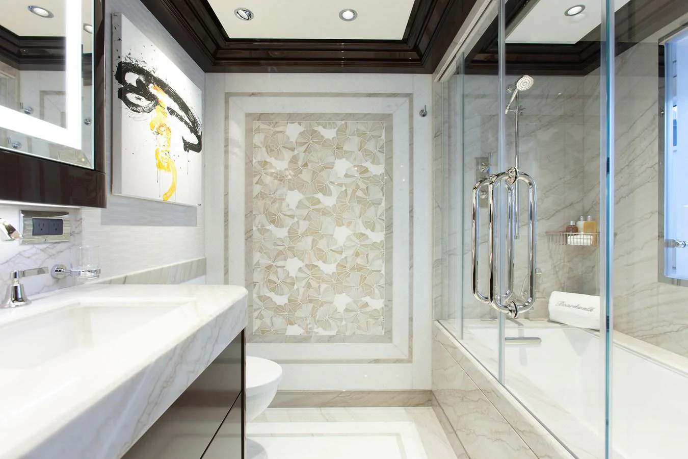 The bathroom features elegant marble finishes and a spacious glass-enclosed shower. aboard BOARDWALK V Yacht for Sale