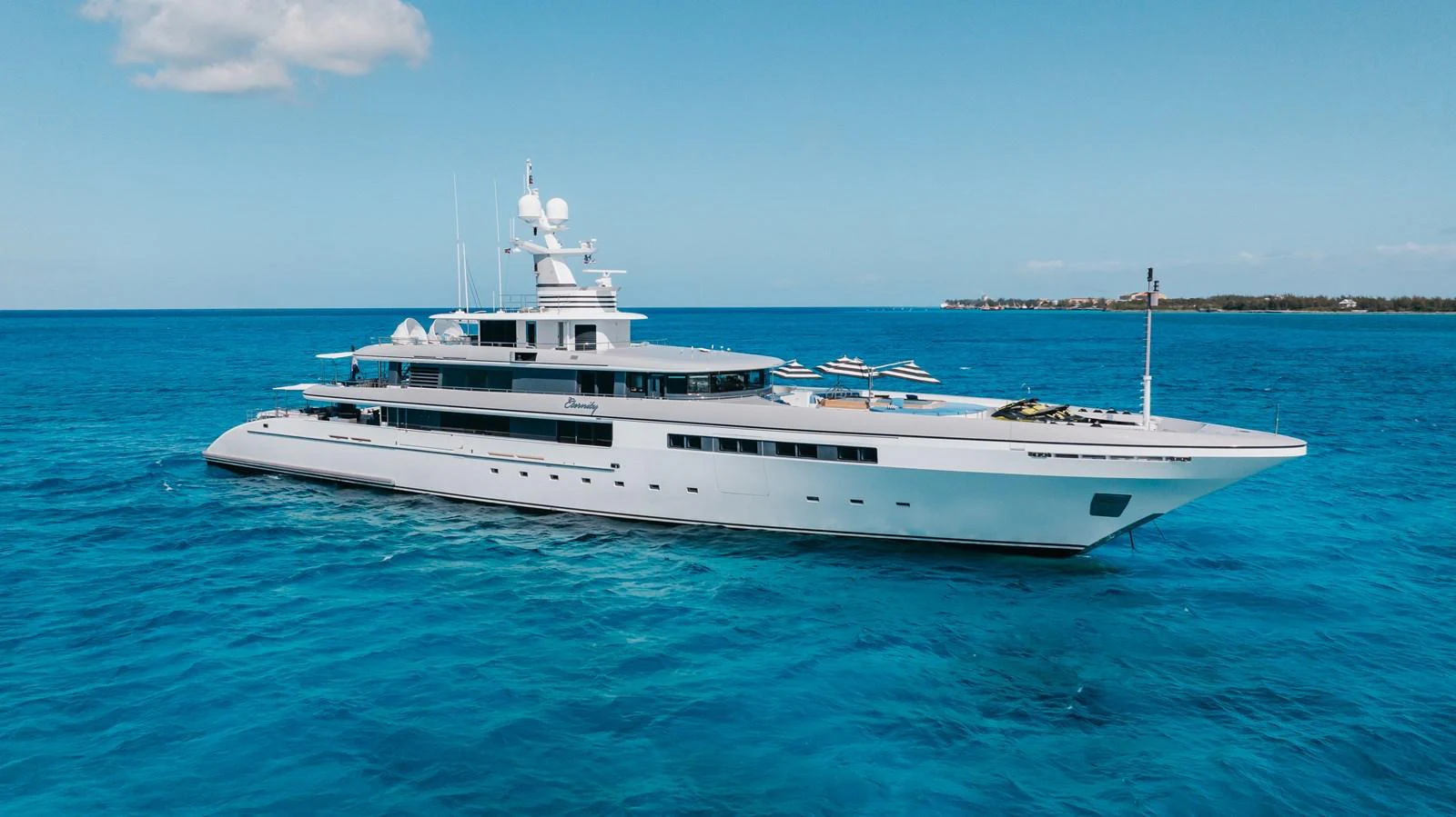 A sleek and modern yacht glides gracefully on the open sea under a clear blue sky. aboard ETERNITY Yacht for Sale