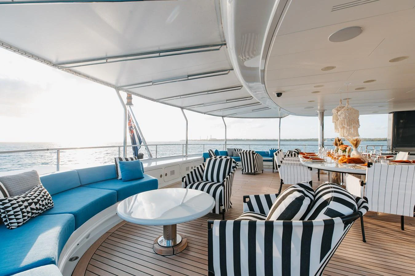 The aft deck features a spacious seating area with stylish striped chairs and a dining table, perfect for enjoying meals with a view of the sea. aboard ETERNITY Yacht for Sale