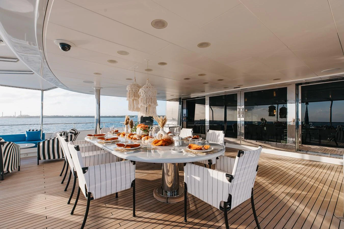 The aft deck features an elegant dining area with a large table set for a meal, surrounded by stylish seating and a beautiful view of the water. aboard ETERNITY Yacht for Sale