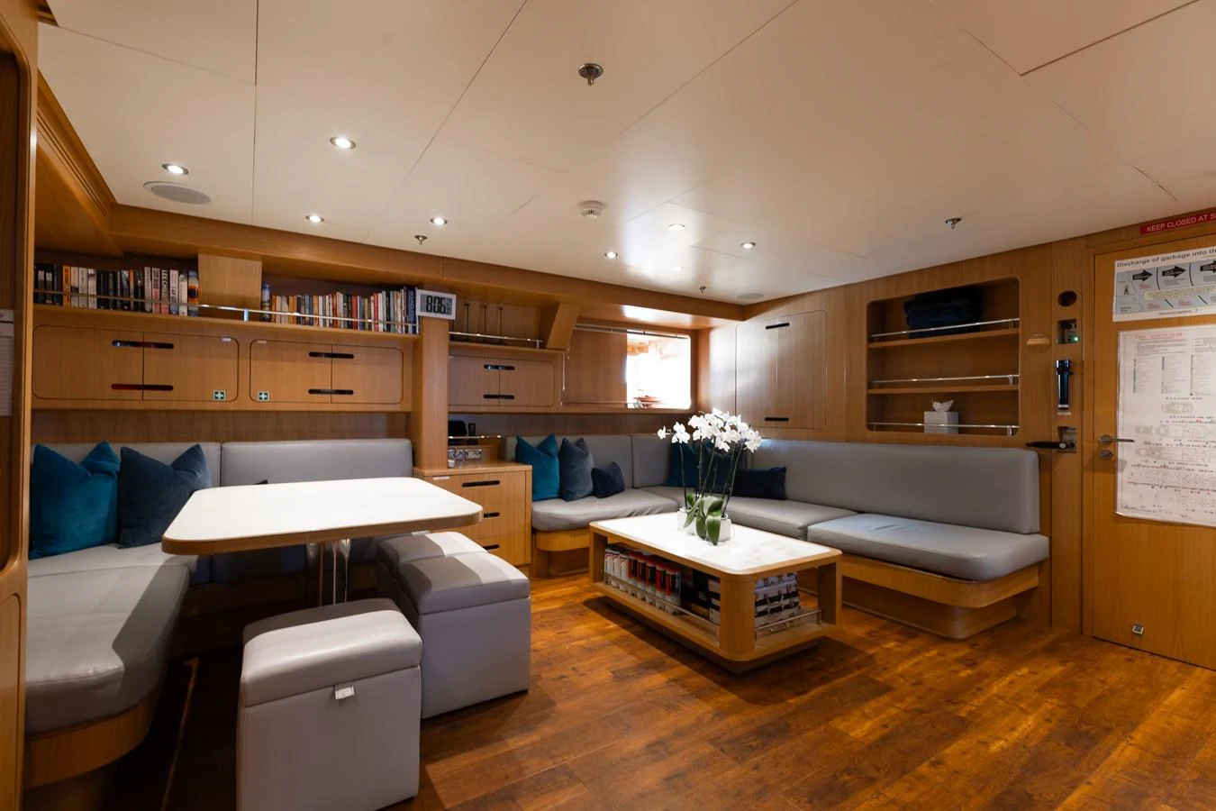 The yacht's salon features a cozy seating area with a dining table and elegant decor. aboard ETERNITY Yacht for Sale