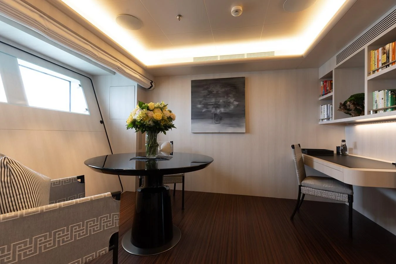 A sophisticated interior space featuring a dining table, comfortable seating, and a work area with bookshelves. aboard ETERNITY Yacht for Sale