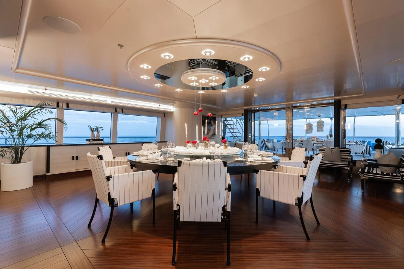 The elegant dining area features a round table with stylish chairs, set against a backdrop of large windows offering stunning sea views. aboard ETERNITY Yacht for Sale