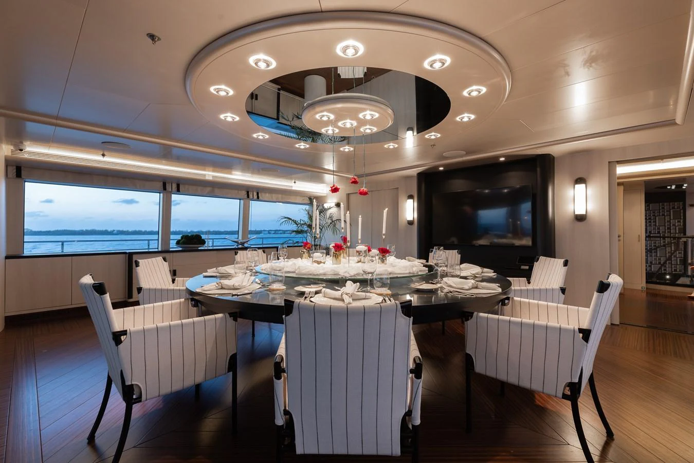 The elegant dining area features a large round table with luxurious seating and ambient lighting. aboard ETERNITY Yacht for Sale