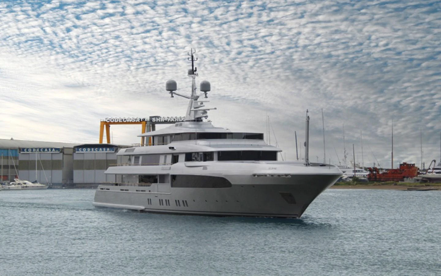 A sleek and modern yacht is cruising through calm waters near a shipyard. aboard REGINA D'ITALIA Yacht for Sale