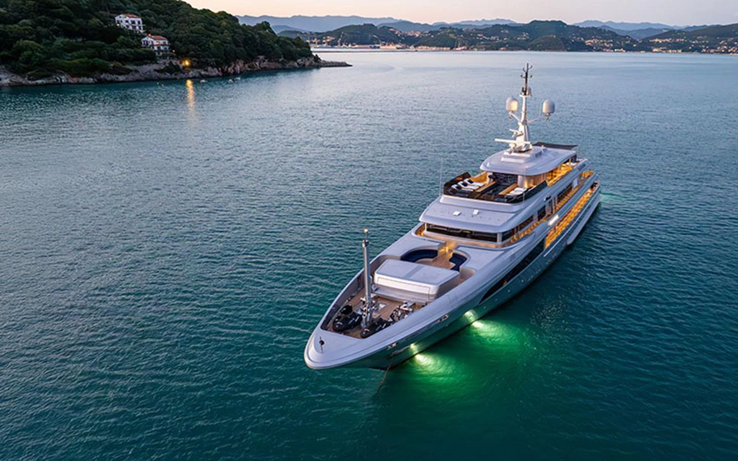 A luxurious yacht glides through serene waters with a picturesque coastal backdrop. aboard REGINA D'ITALIA Yacht for Sale