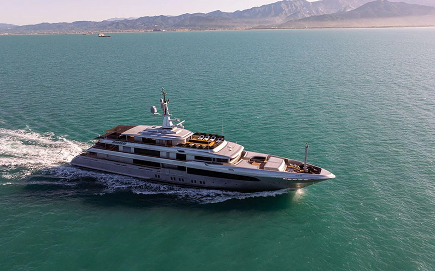 A luxurious yacht cruises through calm waters with a scenic mountain backdrop. aboard REGINA D'ITALIA Yacht for Sale