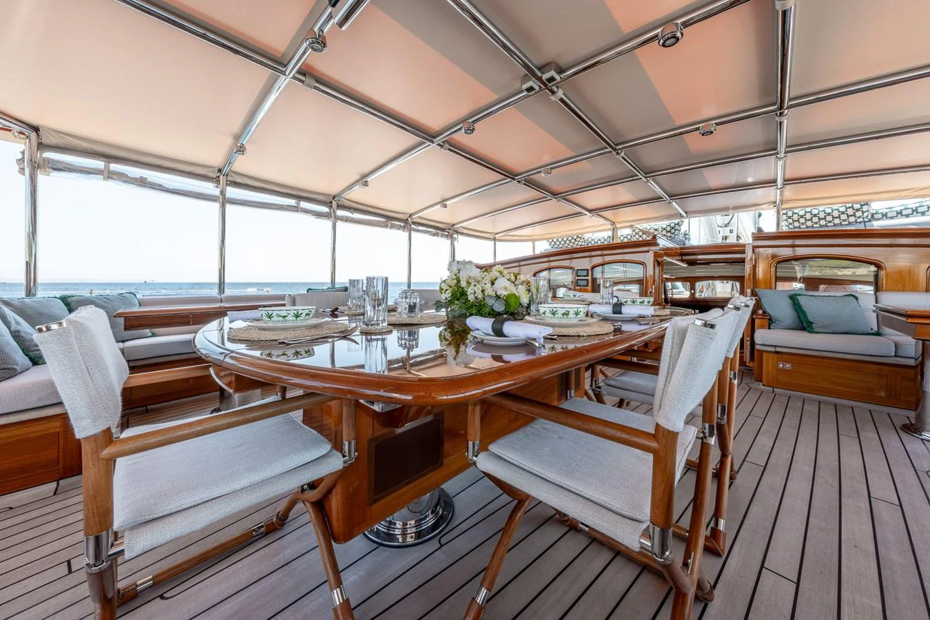 The yacht's dining area features elegant wooden furniture and a spacious, covered setting for alfresco meals. aboard ATHOS Yacht for Sale