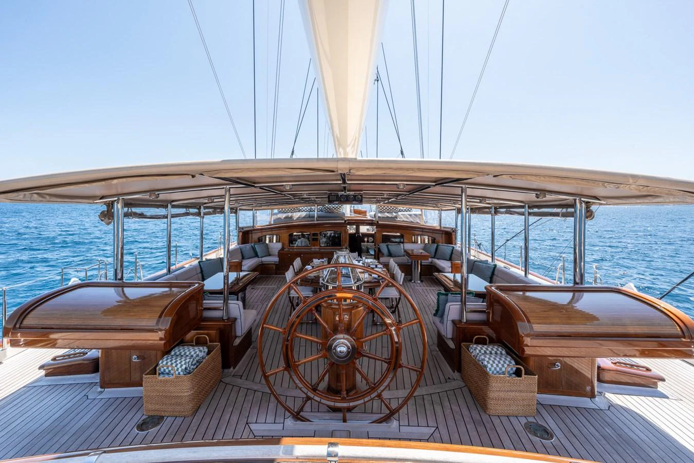 The yacht's aft deck features a spacious and elegant seating area with a classic wooden helm. aboard ATHOS Yacht for Sale