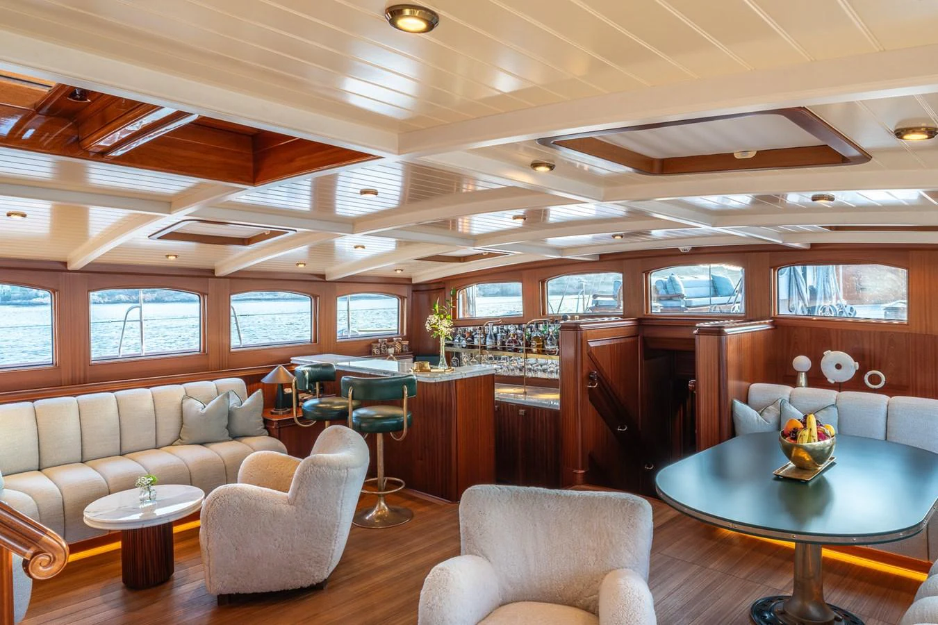The salon features elegant seating, a bar area, and large windows for natural light and scenic views. aboard ATHOS Yacht for Sale